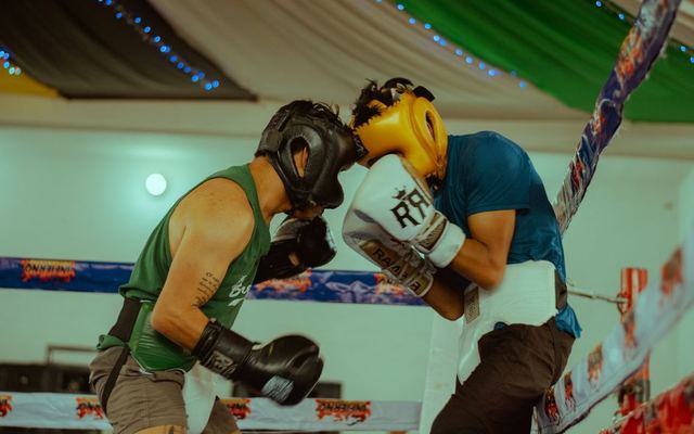 Two boxers engaged in a thrilling match wearing protective headgear and gloves.
