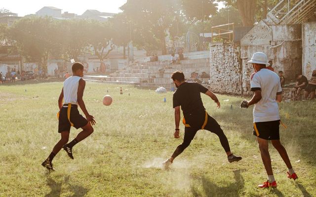 A lively game of flag football with three players on a sunny outdoor field.