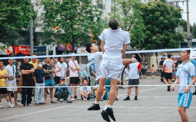 Exciting outdoor footvolley match with spectators cheering lively players.