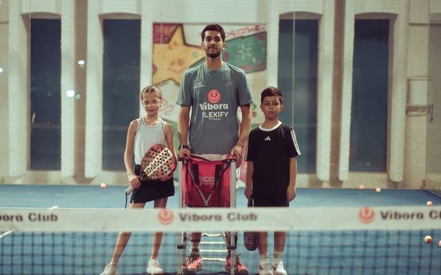Tennis coach with two young players indoors at Vibora Club.