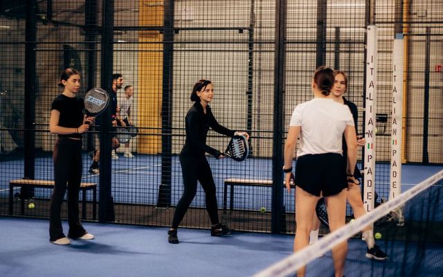 Indoor padel tennis game with multiple players preparing for a match.