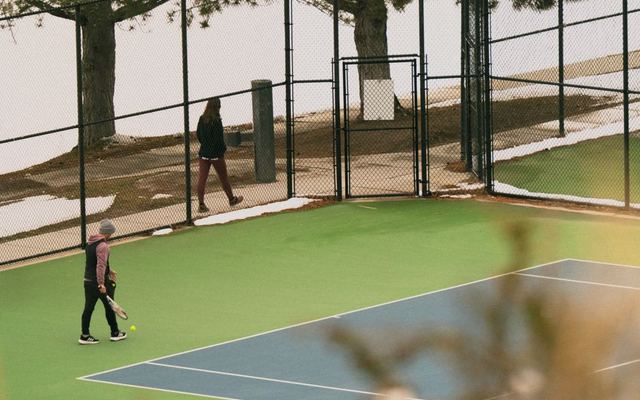 Tennis match in Salt Lake City amidst snow during spring, featuring players on a vibrant court.