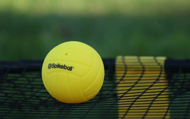 Close-up of a yellow Spikeball on a net, showcasing outdoor summer sport equipment.