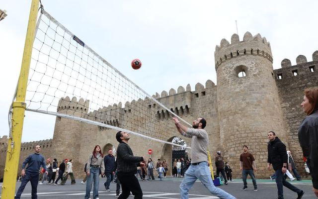 Group playing volleyball near an ancient castle wall, capturing the blend of sports and history.