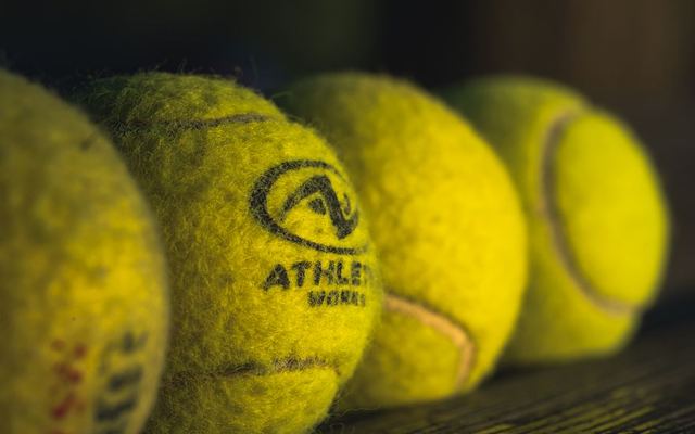 Detailed close-up of yellow tennis balls on a rustic wooden surface with textured branding.
